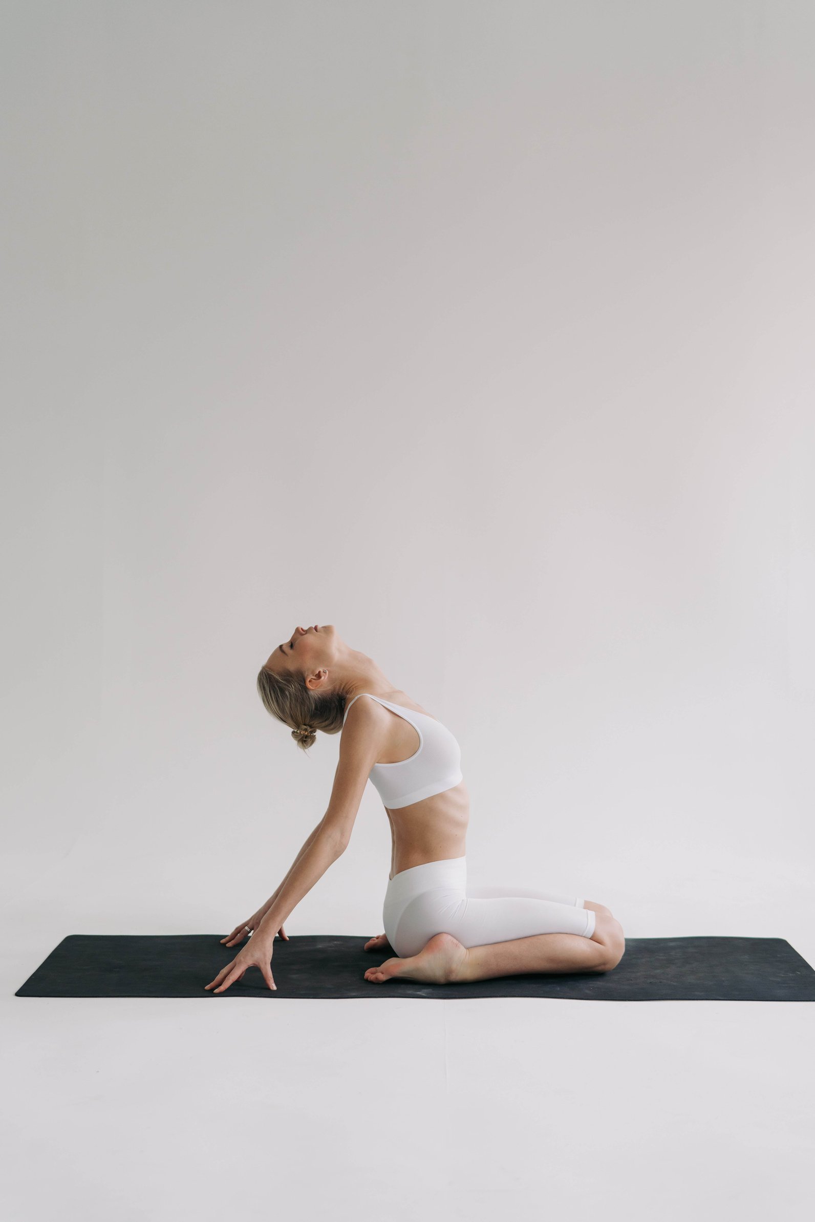 A Woman in Tank Top Sitting on the Yoga Mat